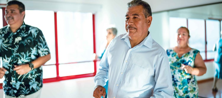 Un hombre latino que pertenece en COVID-19 grupos de alto riesgo, haciendo ejercicios en un grupo de latinos mayores.