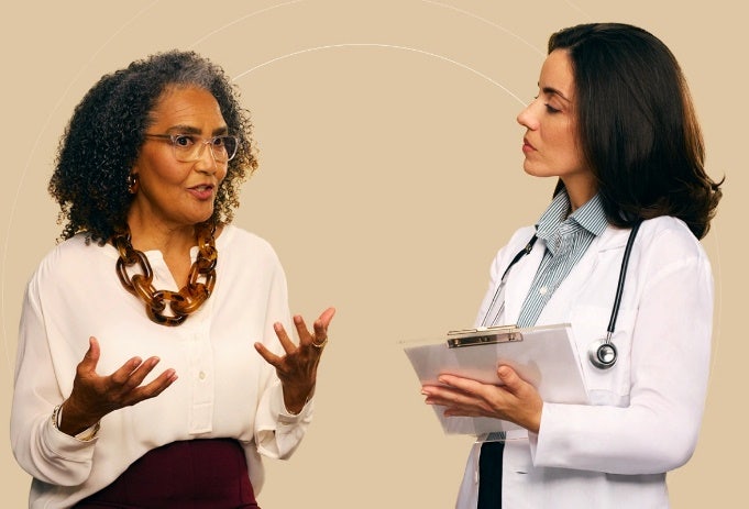Foto de dos mujeres latinas donde una doctora está hablando con una señora mayor sobre cómo prevenir COVID-19.