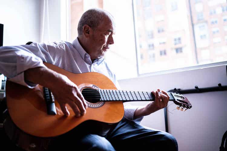 Foto de un hombre Latino que tiene COVID-19 factores de alto riesgo tocando su guitarra.