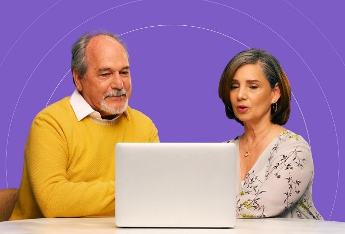 Una pareja latina que pertenece en COVID-19 grupos de alto riesgo está leyendo información en un sitio web.