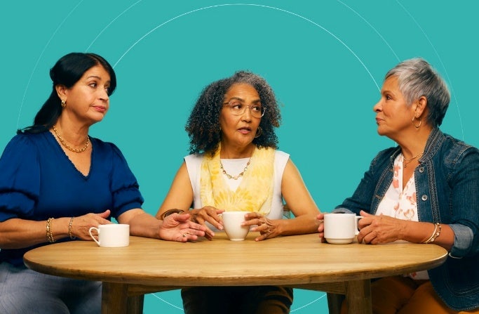 Tres señoras mayor con COVID-19 factores de alto riesgo están sentados en una messa hablando sobre tasas de café.